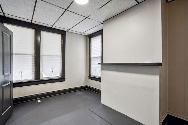 empty room featuring baseboards, dark wood-type flooring, and a paneled ceiling