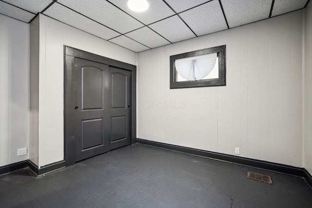 unfurnished bedroom with baseboards, visible vents, and a drop ceiling