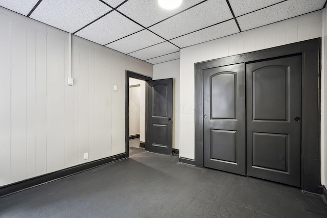 unfurnished bedroom with a closet, a drop ceiling, and baseboards