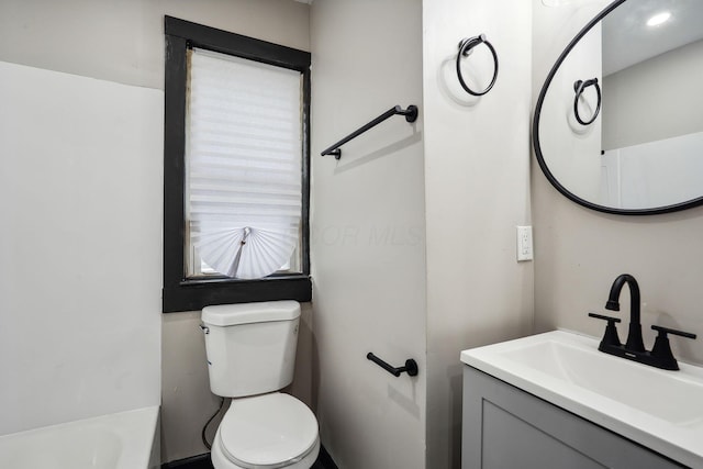 bathroom with vanity, toilet, and a tub to relax in