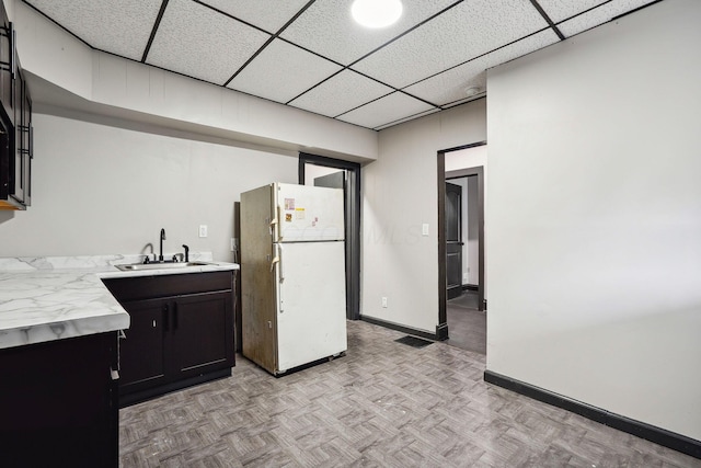 kitchen with visible vents, freestanding refrigerator, a sink, light countertops, and a paneled ceiling