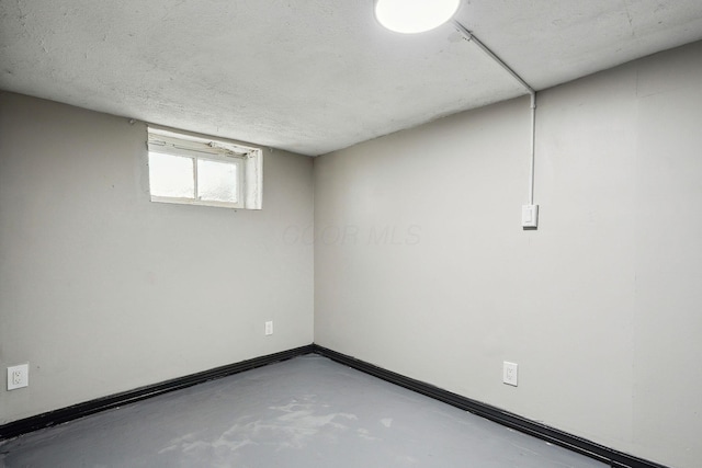 basement with baseboards and a textured ceiling