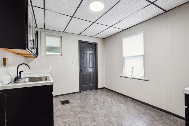 kitchen with a sink, visible vents, a drop ceiling, and light countertops