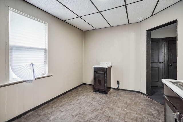 interior space featuring a paneled ceiling and baseboards