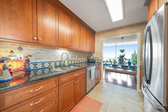 kitchen featuring a sink, dark stone counters, brown cabinets, and stainless steel appliances