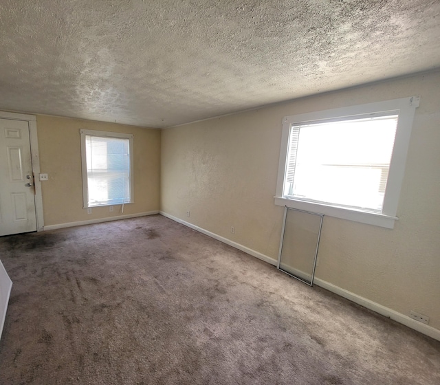 carpeted spare room with baseboards, a textured ceiling, and a textured wall