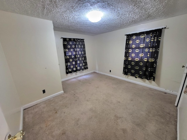 empty room with carpet flooring, baseboards, and a textured ceiling