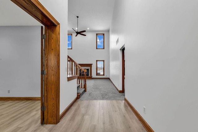 foyer entrance with baseboards, a towering ceiling, stairs, and light wood finished floors