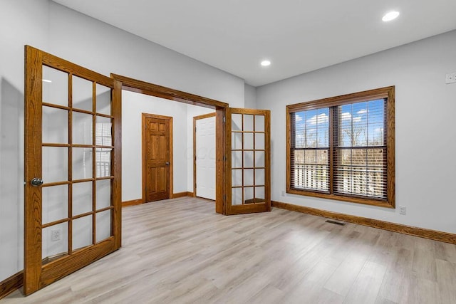 spare room featuring recessed lighting, french doors, baseboards, and light wood-style floors