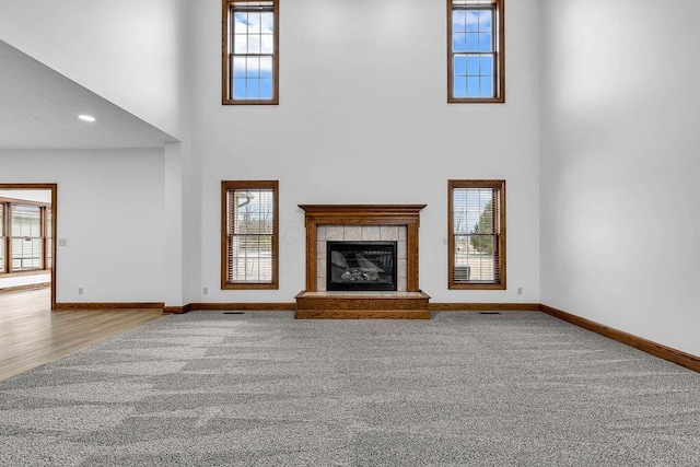 unfurnished living room featuring baseboards, carpet floors, a healthy amount of sunlight, and a fireplace