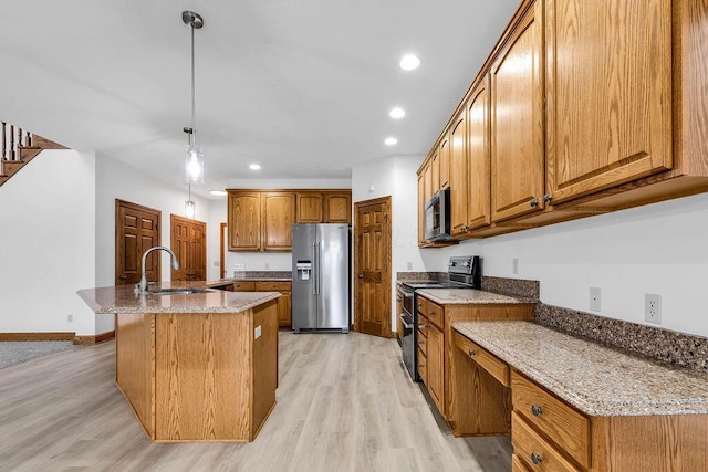 kitchen with brown cabinetry, light wood-style floors, appliances with stainless steel finishes, and a sink