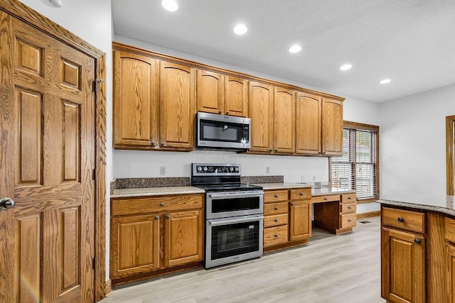 kitchen with brown cabinets, light wood-style floors, and appliances with stainless steel finishes