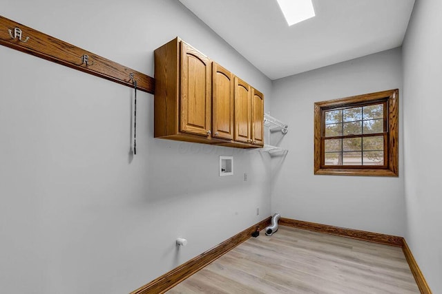 laundry room featuring baseboards, hookup for a washing machine, a skylight, light wood-style floors, and cabinet space