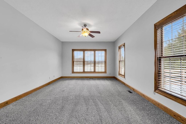 empty room with carpet flooring, a ceiling fan, and baseboards