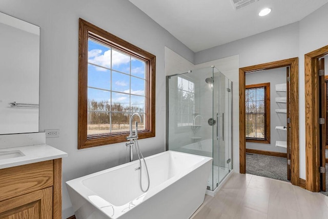 full bathroom with visible vents, a shower stall, a freestanding bath, and vanity