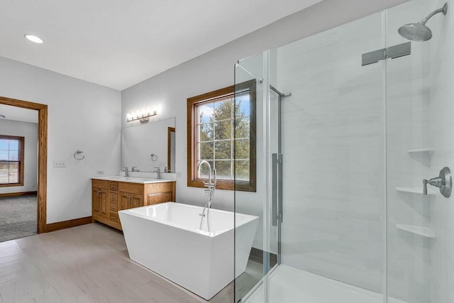 full bathroom featuring a sink, a shower stall, a freestanding bath, and double vanity