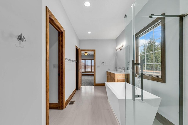 full bathroom featuring visible vents, baseboards, recessed lighting, a soaking tub, and vanity