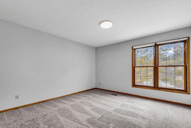 carpeted empty room featuring a textured ceiling and baseboards