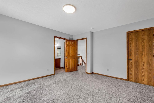 unfurnished bedroom with visible vents, a textured ceiling, baseboards, and carpet