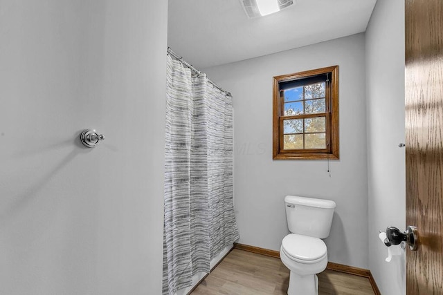 full bathroom featuring a shower with curtain, wood finished floors, visible vents, baseboards, and toilet