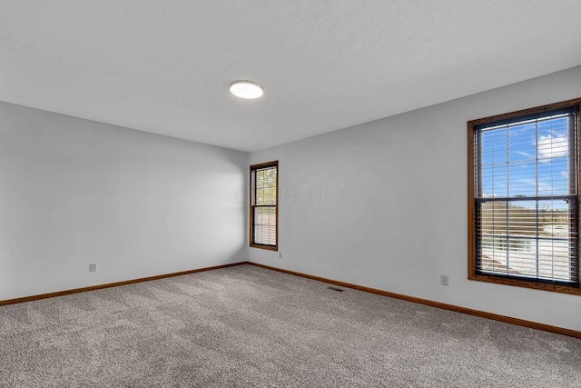 carpeted empty room featuring visible vents and baseboards