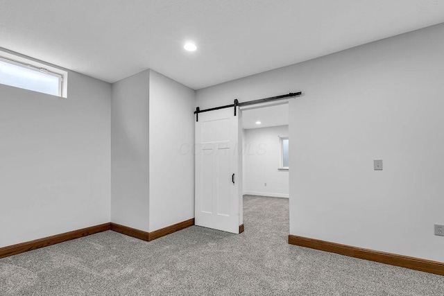 below grade area with carpet flooring, recessed lighting, baseboards, and a barn door