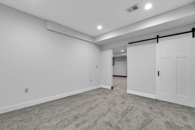 below grade area with visible vents, recessed lighting, a barn door, carpet floors, and baseboards