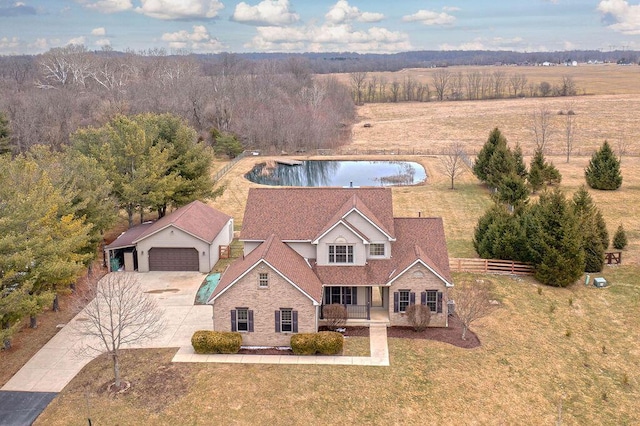 view of front of home with a front yard, fence, driveway, a water view, and a garage