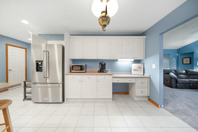 kitchen with light tile patterned floors, built in study area, light countertops, appliances with stainless steel finishes, and light carpet