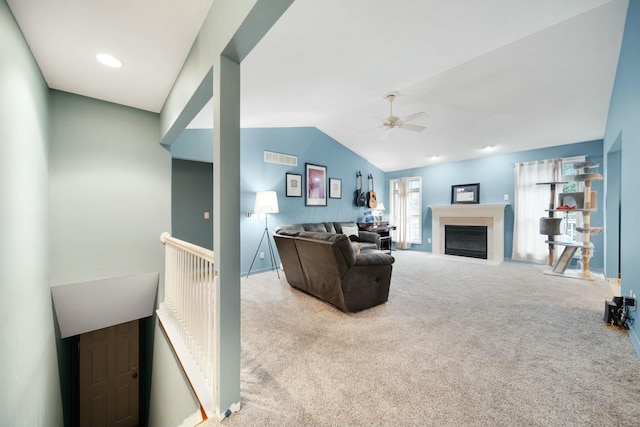 living room with visible vents, a fireplace with flush hearth, a ceiling fan, carpet floors, and vaulted ceiling