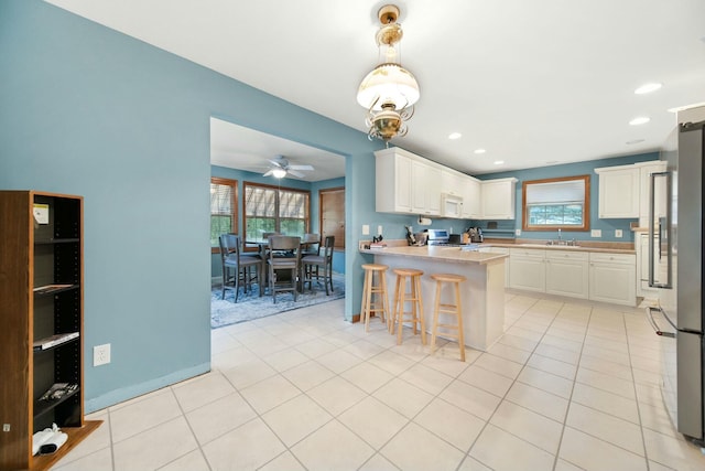 kitchen featuring stove, light tile patterned floors, white microwave, and high end fridge