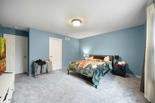 carpeted bedroom featuring visible vents, baseboards, and a textured ceiling