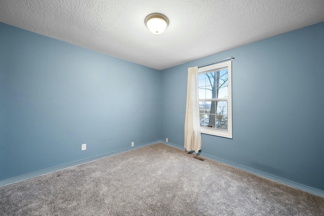 spare room with visible vents, baseboards, a textured ceiling, and carpet flooring