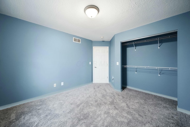 unfurnished bedroom featuring carpet, baseboards, visible vents, a closet, and a textured ceiling