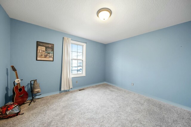 unfurnished room with baseboards, visible vents, carpet floors, and a textured ceiling