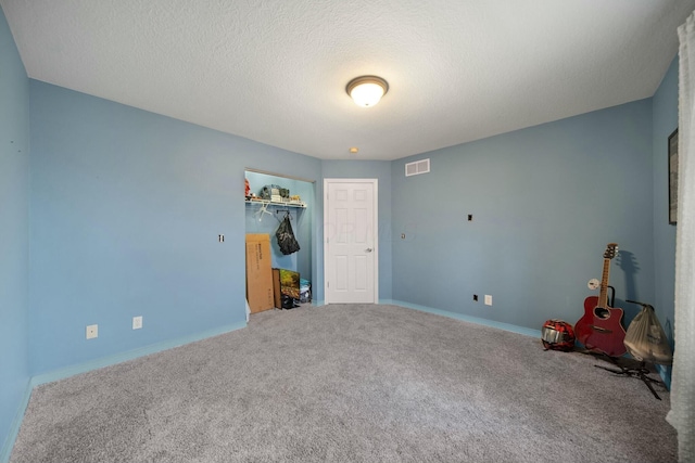 unfurnished bedroom with visible vents, a textured ceiling, a closet, carpet, and baseboards