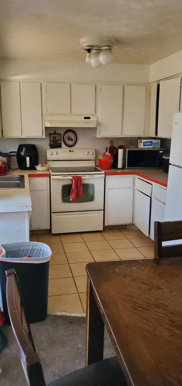 kitchen featuring white appliances, light tile patterned flooring, a sink, light countertops, and white cabinets