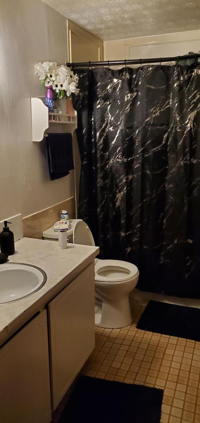 full bathroom with tile patterned flooring, toilet, a shower with shower curtain, vanity, and a textured ceiling