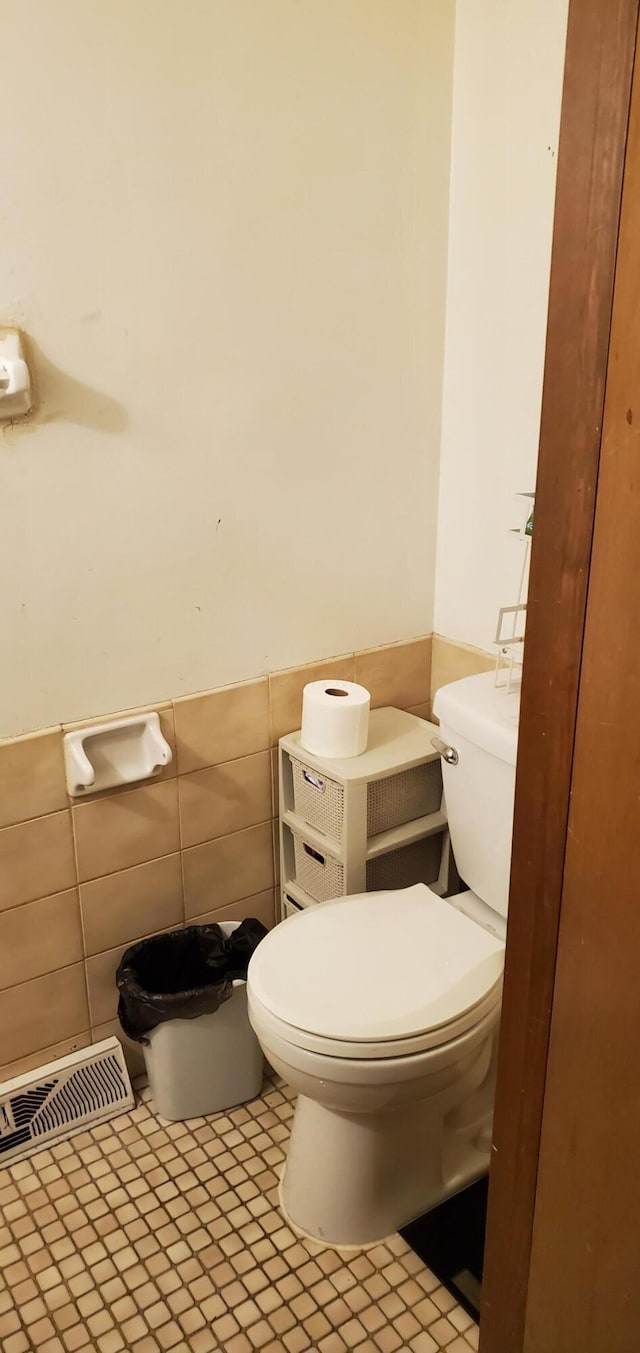 bathroom featuring visible vents, toilet, tile walls, and a wainscoted wall