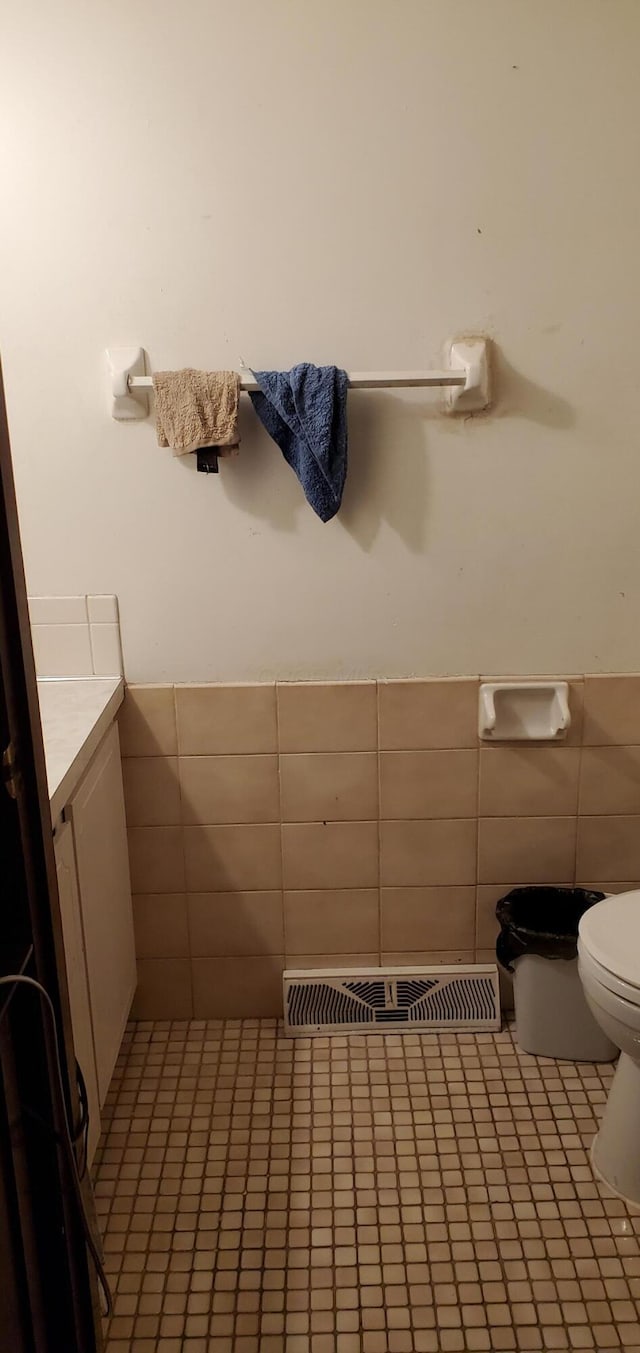 half bath featuring vanity, visible vents, tile walls, toilet, and tile patterned floors