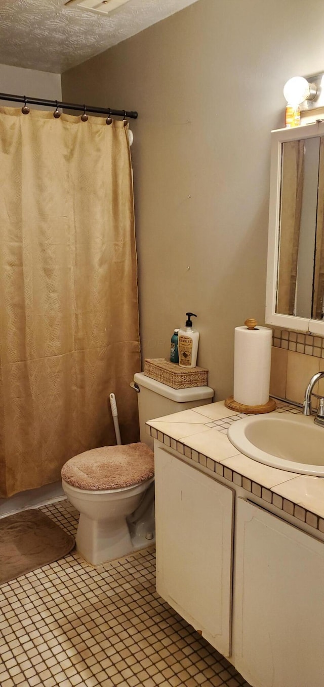 full bath with tile patterned floors, toilet, a textured ceiling, and vanity