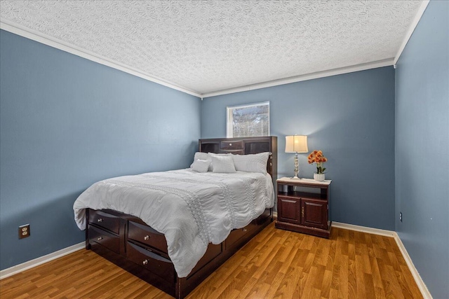 bedroom featuring baseboards, a textured ceiling, wood finished floors, and crown molding