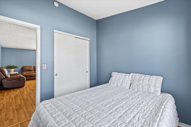 bedroom with wood finished floors and a closet