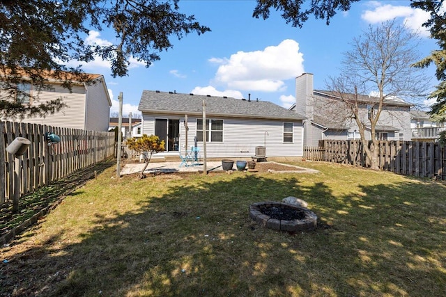 back of house featuring a patio, a fenced backyard, a yard, a fire pit, and a chimney