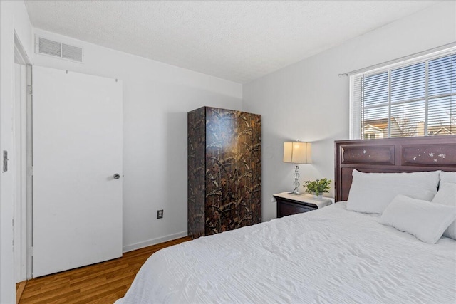 bedroom featuring visible vents, a textured ceiling, and wood finished floors