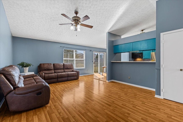 living area with baseboards, a textured ceiling, wood finished floors, and a ceiling fan