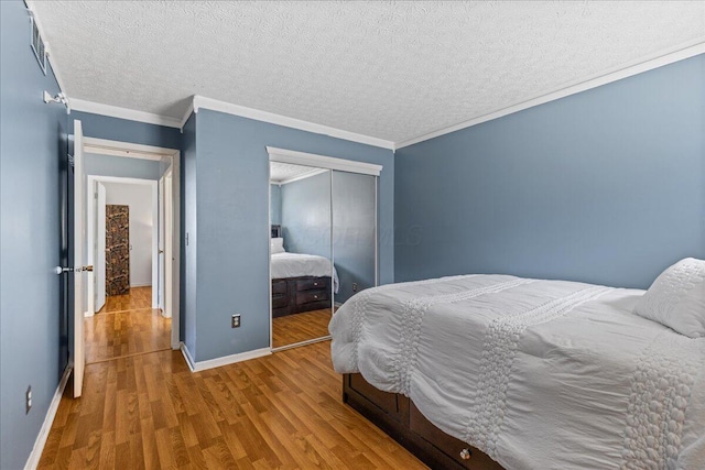 bedroom featuring visible vents, wood finished floors, a closet, and ornamental molding