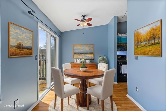 dining space with baseboards, lofted ceiling, wood finished floors, and a ceiling fan