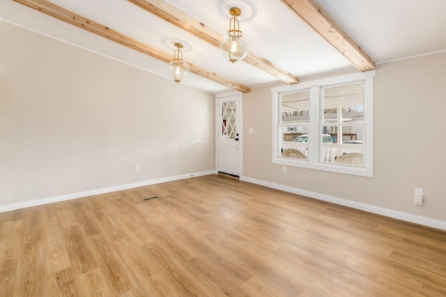 empty room with beamed ceiling, baseboards, and light wood finished floors