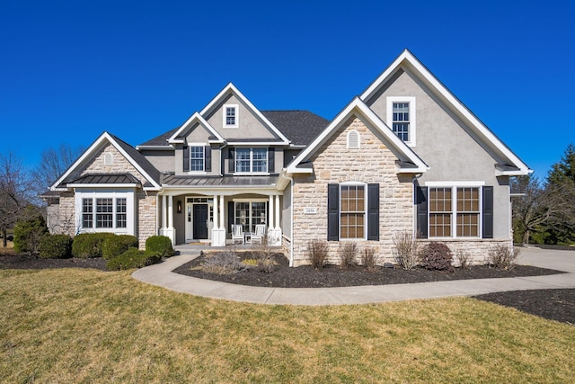 craftsman inspired home featuring stone siding, metal roof, a standing seam roof, and a front yard